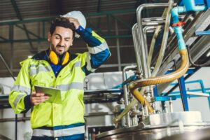 man with clipboard scratching his head under helmet